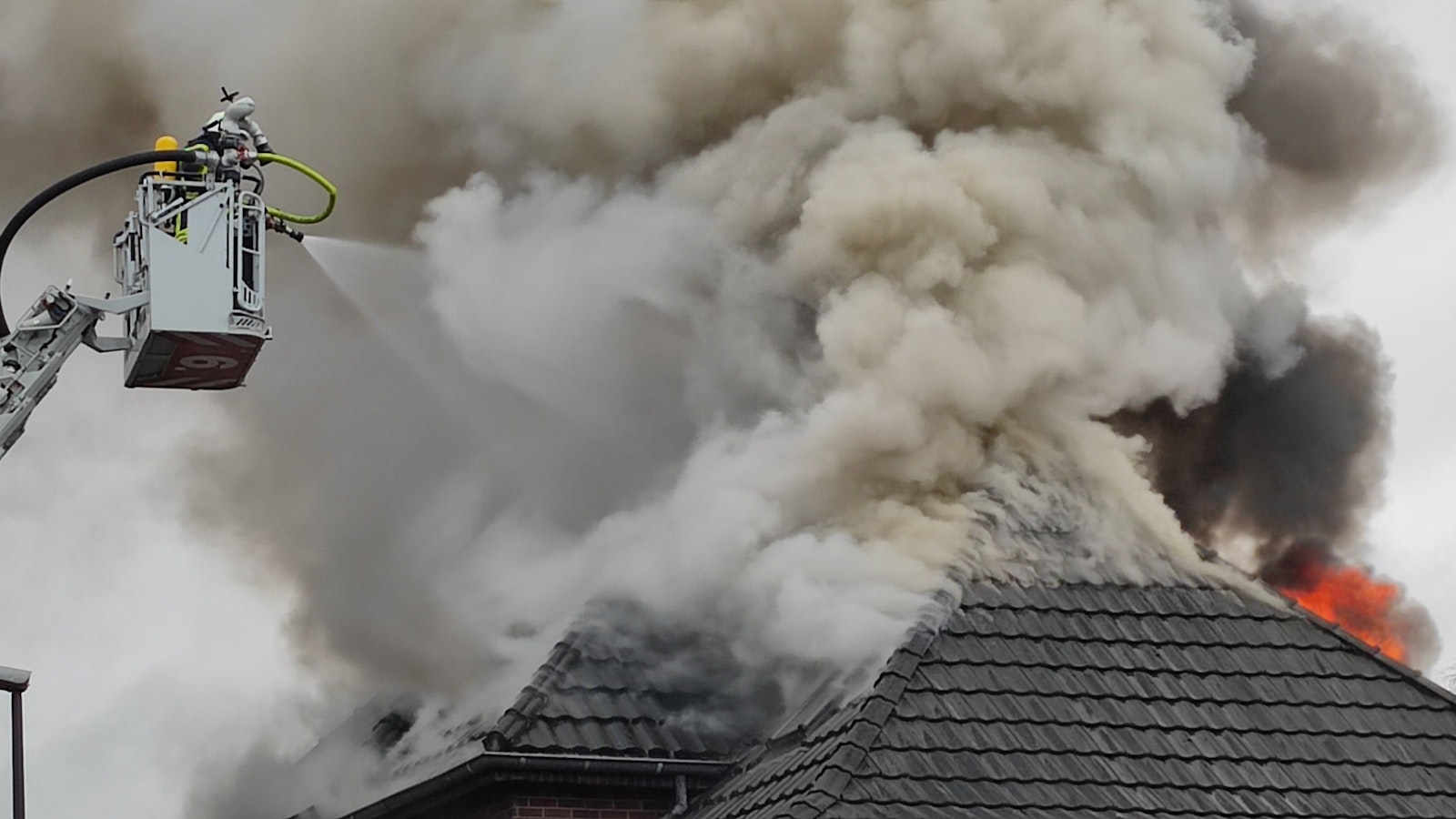 Aus einem Dachstuhl schlagen Flammen und quillt dichter Rauch.