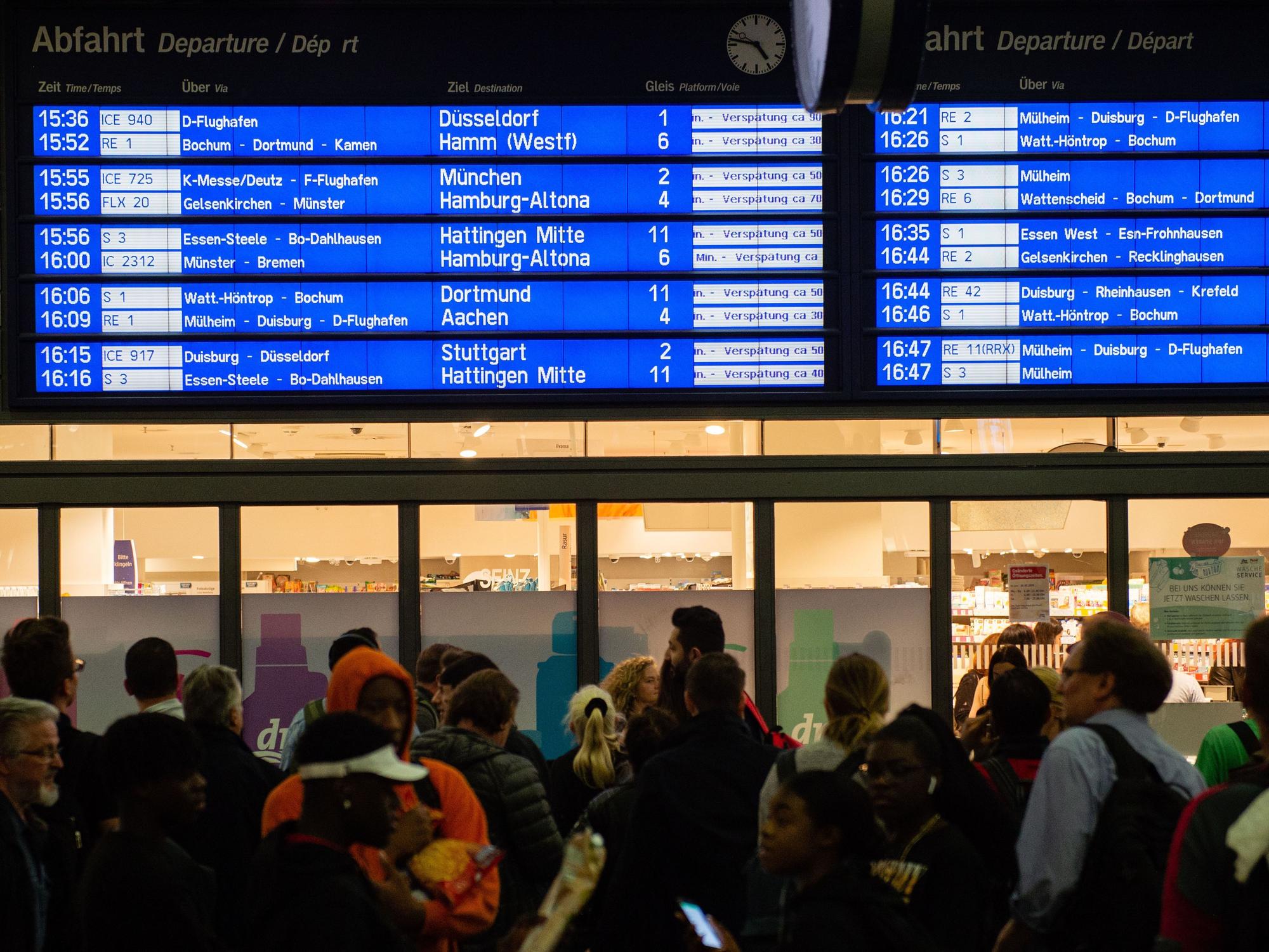 Menschen warten im Hauptbahnhof vor der Anzeigetafel, auf der zahlreiche Zugverspätungen angegeben werden.