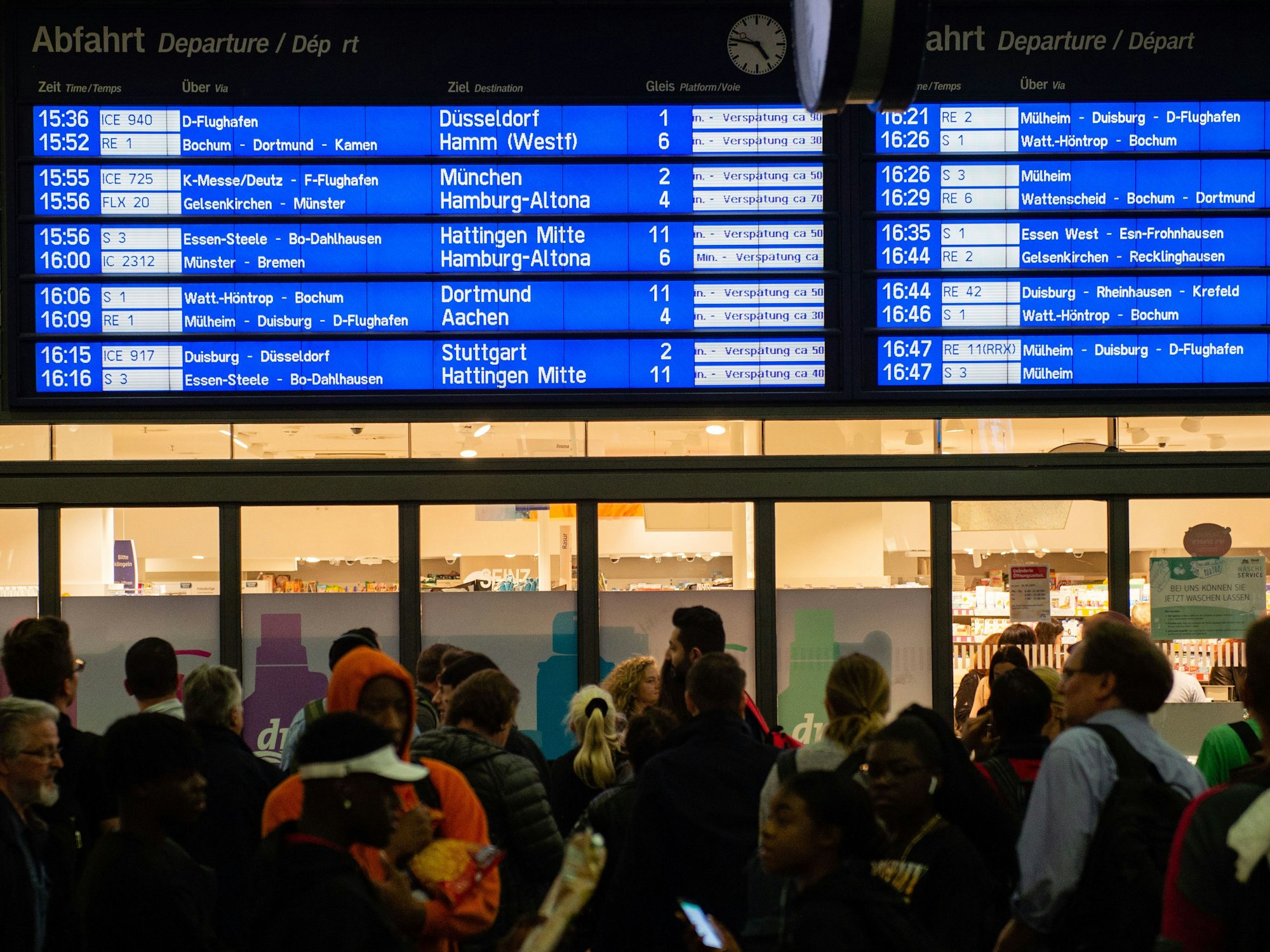 Menschen warten im Hauptbahnhof vor der Anzeigetafel, auf der zahlreiche Zugverspätungen angegeben werden.