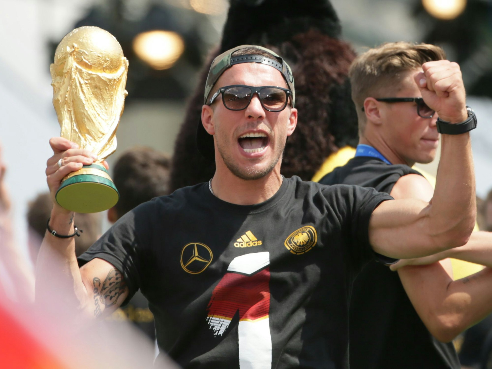 Lukas Podolski jubelt am 15. Juli 2014 beim Empfang der Fußball-Nationalmannschaft in Berlin mit dem WM-Pokal.