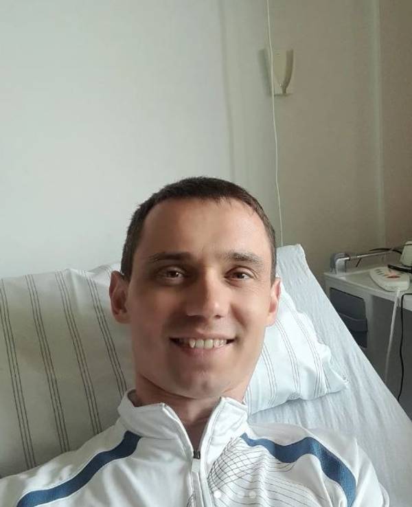 Ein Mann liegt in einem Krankenbett und schaut in die Kamera.