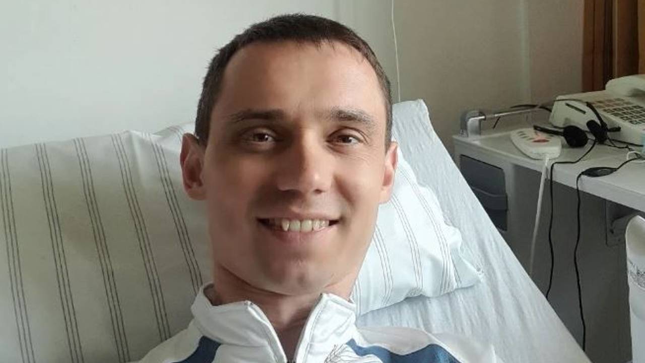 Ein Mann liegt in einem Krankenbett und schaut in die Kamera.