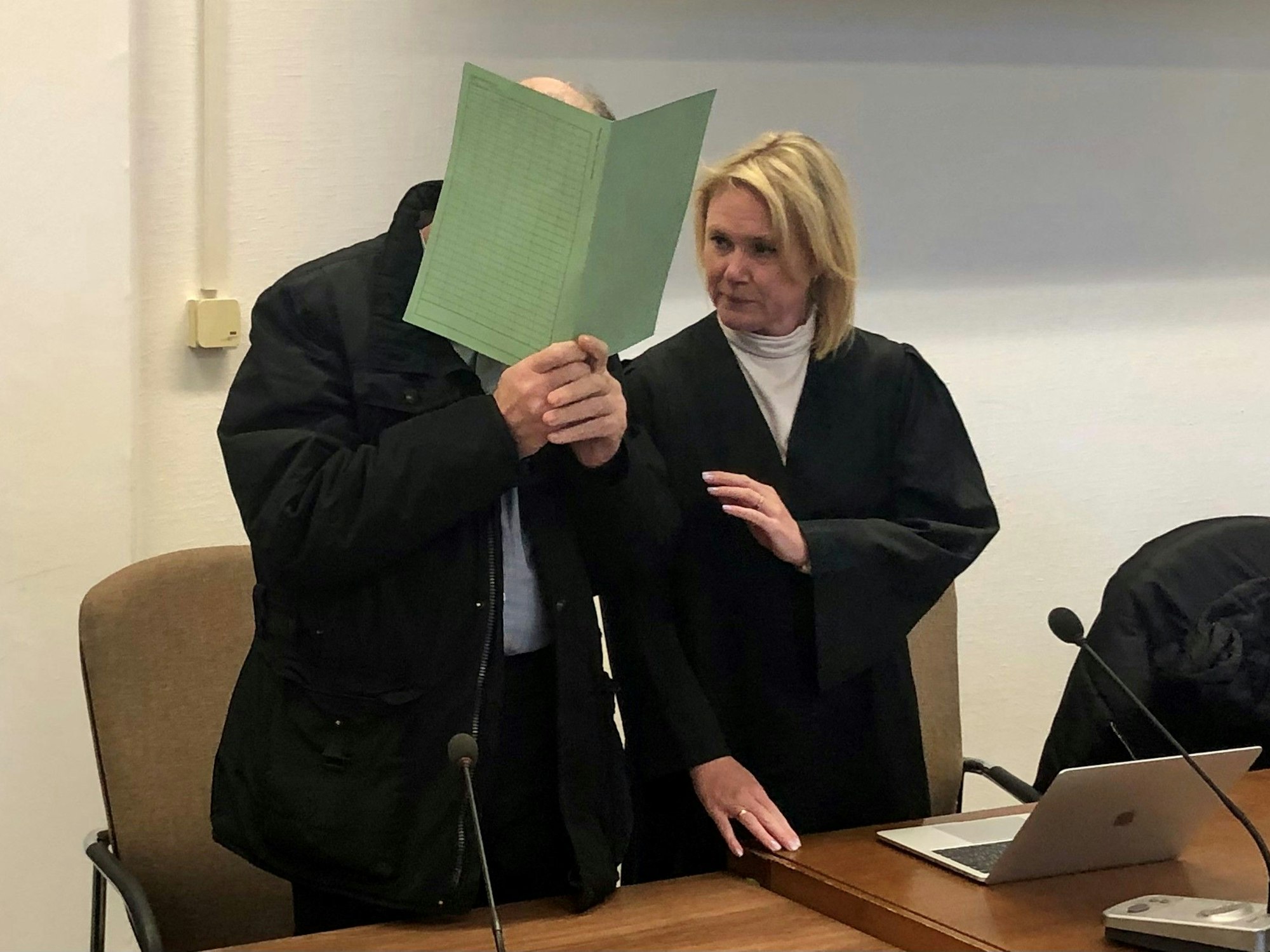 Der Angeklagte steht kurz vor der Urteilsbegründung neben seiner Verteidigerin.