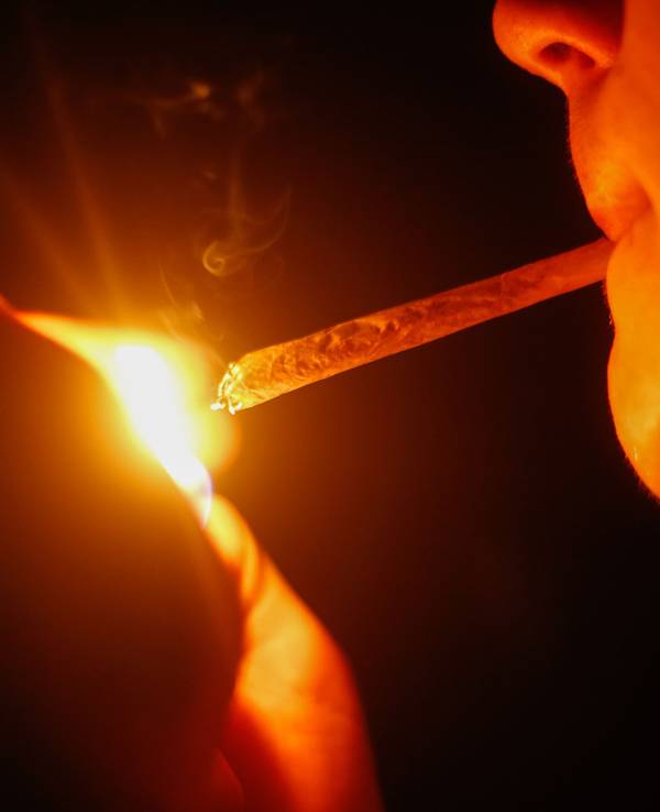Ein junger Mann zündet sich einen Joint an.