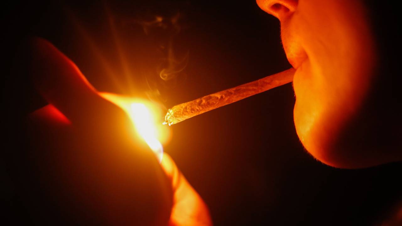 Ein junger Mann zündet sich einen Joint an.