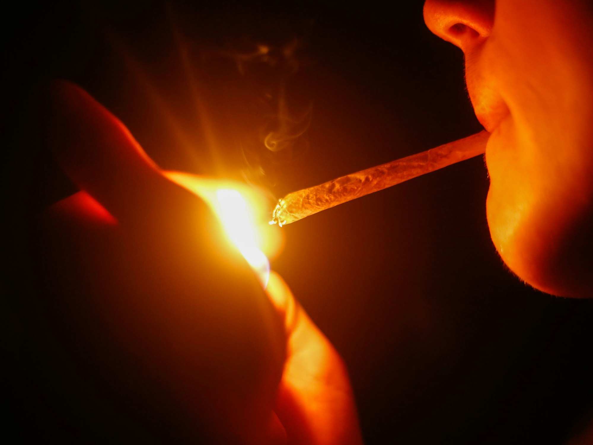 Ein junger Mann zündet sich einen Joint an.