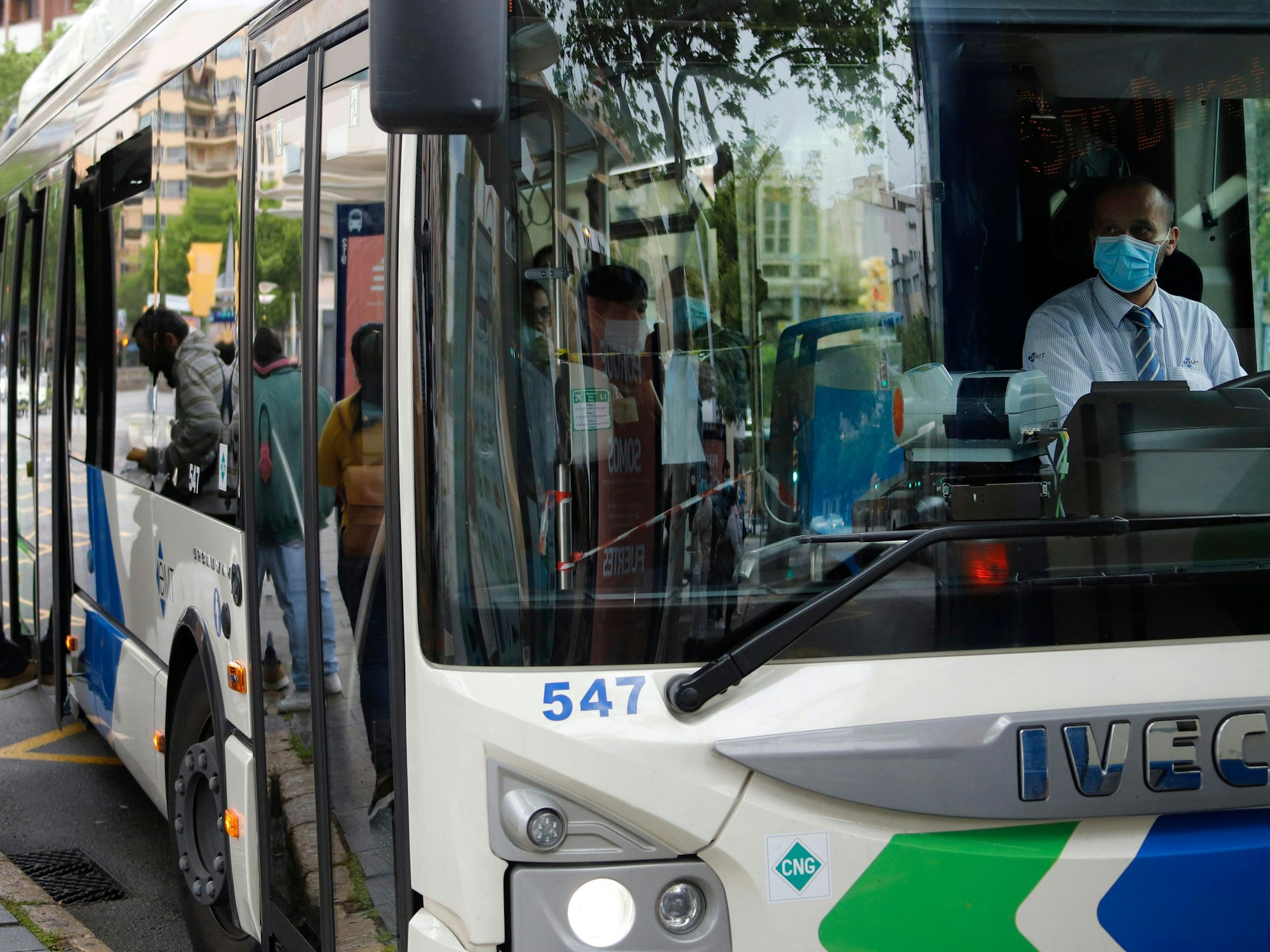 Ein Busfahrer sitzt in einem Linienbus in Spanien, er trägt einen Mund- und Nasenschutz.