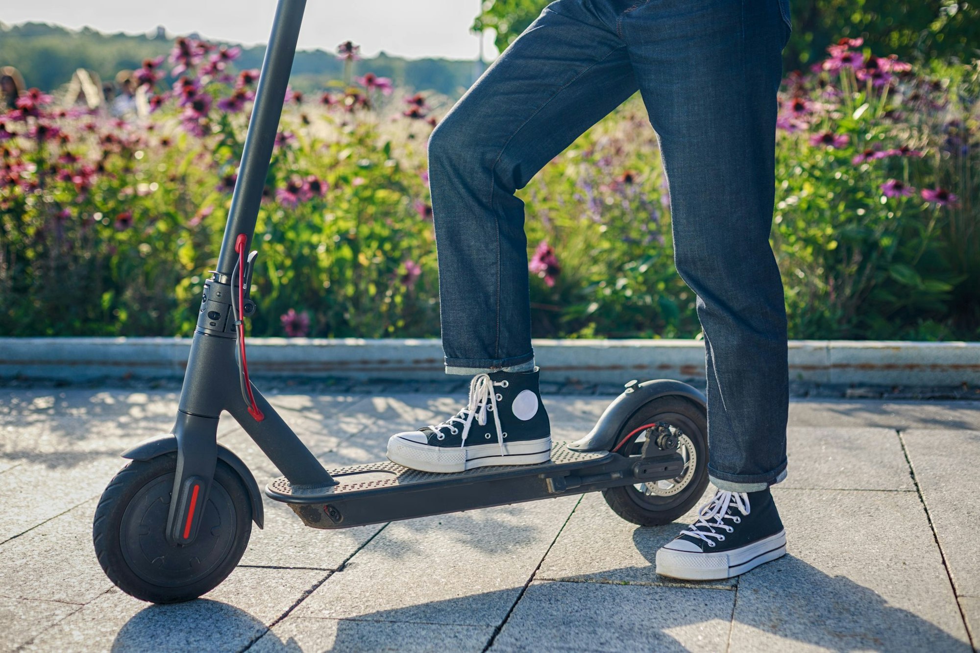 Frau steht mit einem Bein auf ihrem E - Scooter