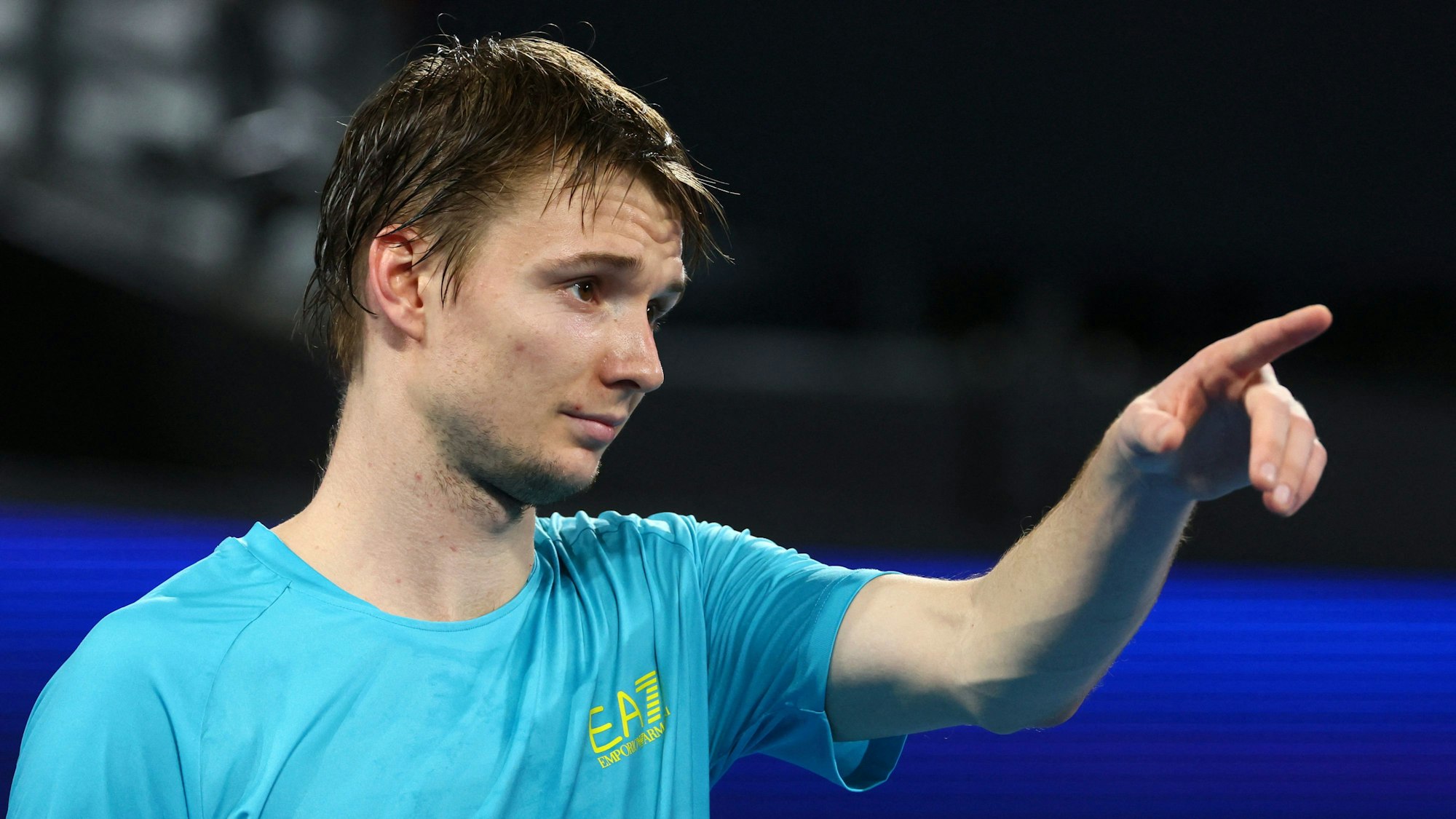 Alexander Bublik reagiert nach einem Ballwechsel und zeigt auf etwas.