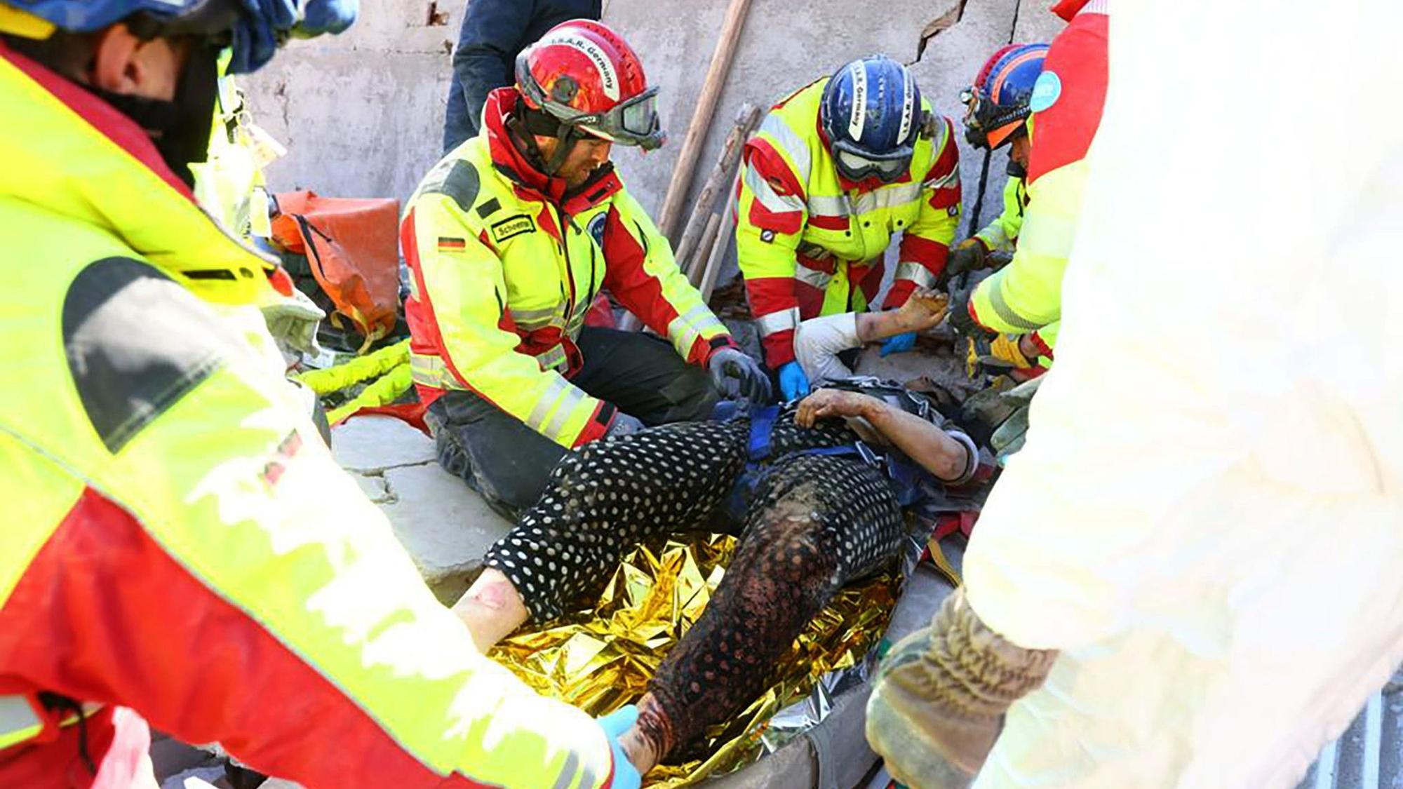 Rettungskräfte heben die Frau aus den Trümmern.