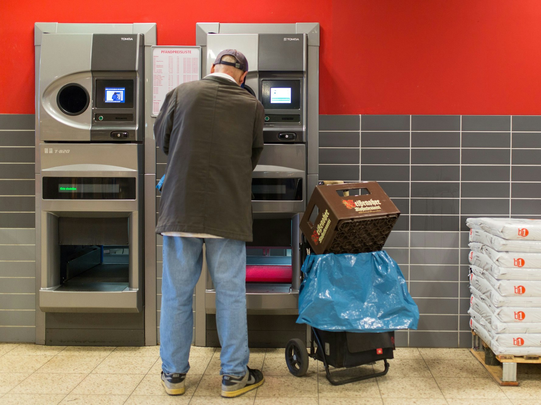 Ein Mann gibt in Berlin seine Pfandflaschen an einem Pfandflaschenautomaten ab.