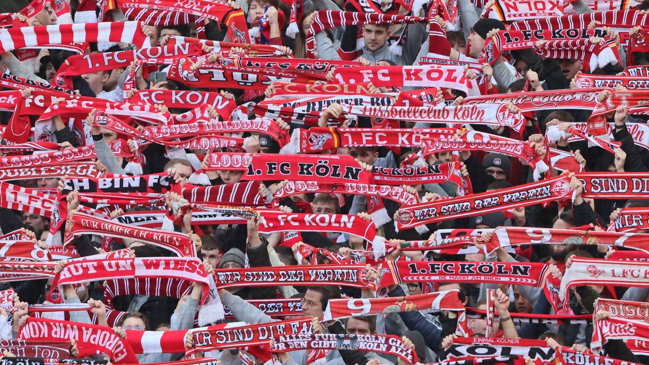 Fans des 1. FC Köln halten ihre Schals hoch.