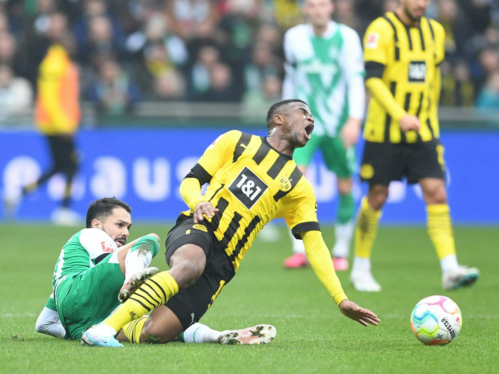Dortmunds Youssoufa Moukoko (r) wird von Werders Leonardo Bittencourt gefoult.