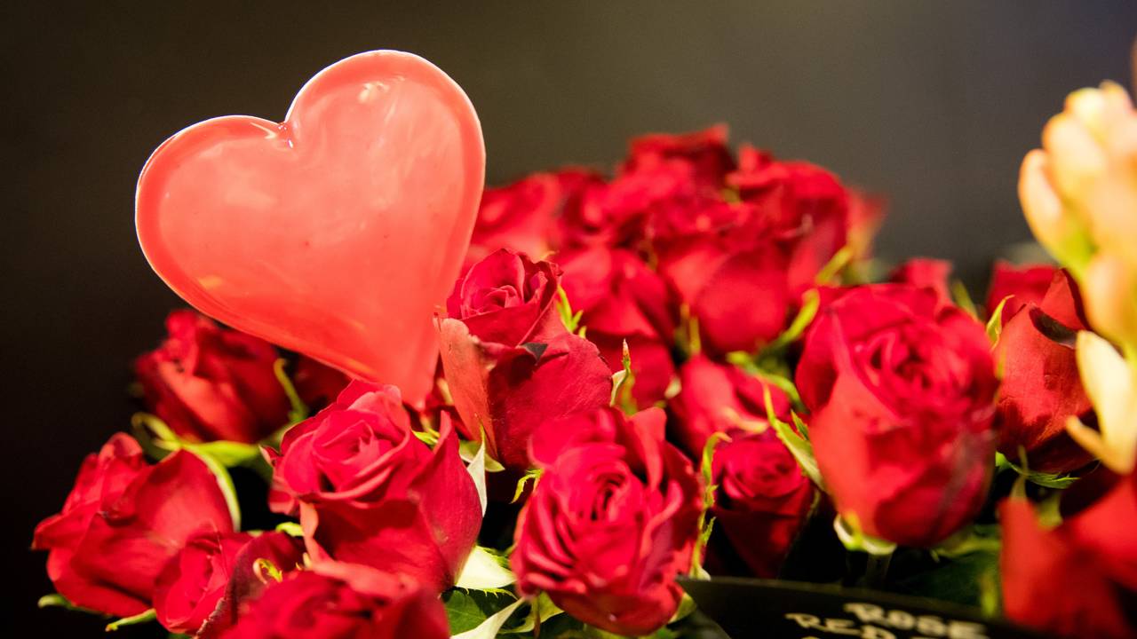 Ein rotes Herz in einem Strauß roter Rosen.