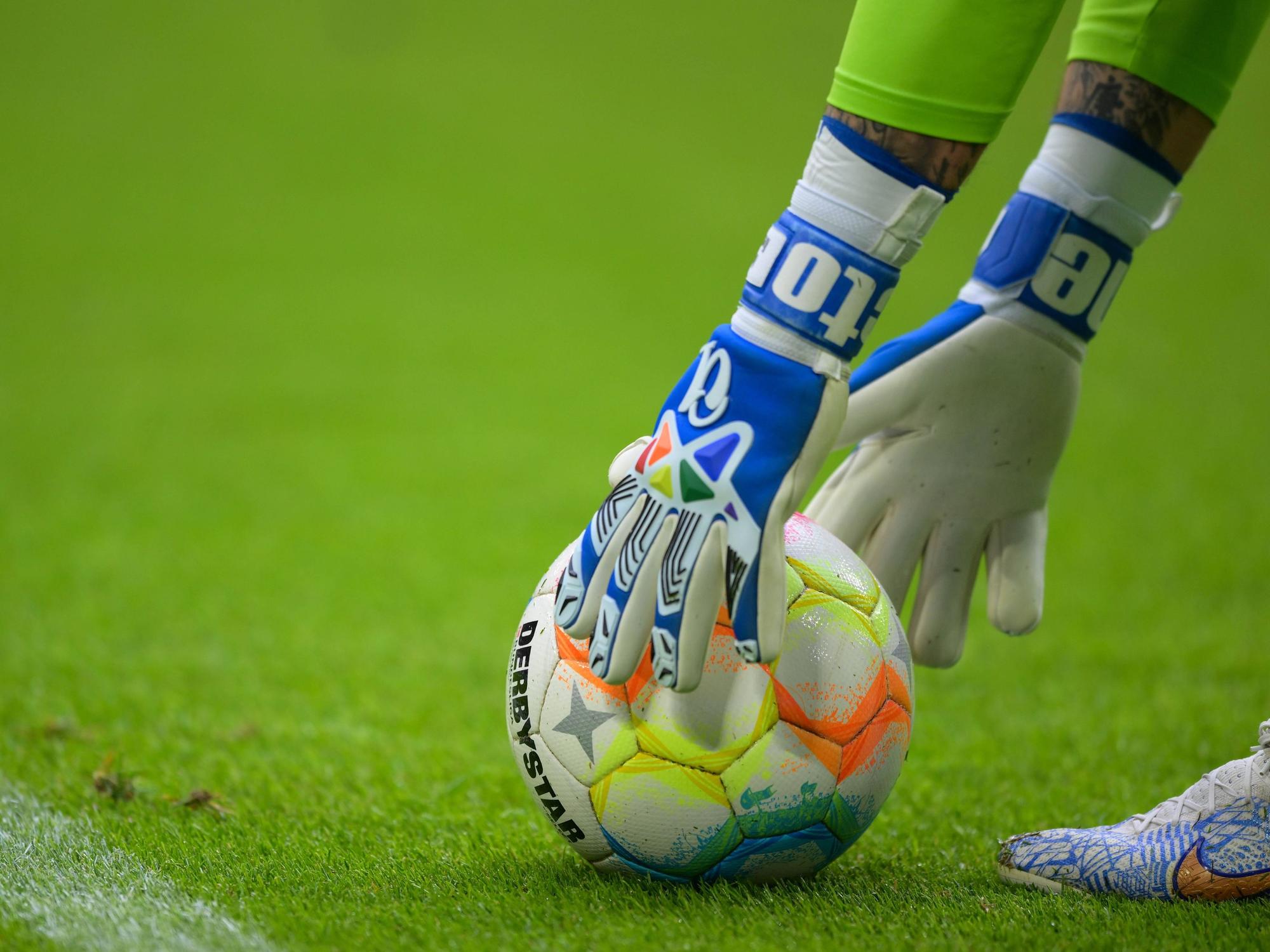 Hände in Torwarthandschuhen greifen nach dem Ball.