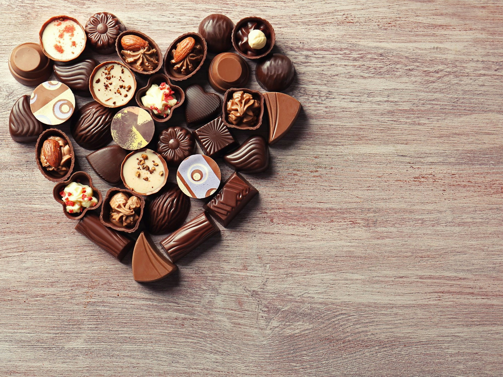 Pralinen liegen als Herz geformt auf einem Tisch.