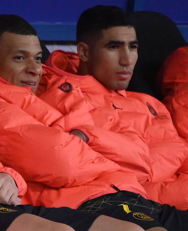Lionel Messi, Kylian Mbappé und Achraf Hakimi sitzen nebeneinander auf der Auswechselbank.