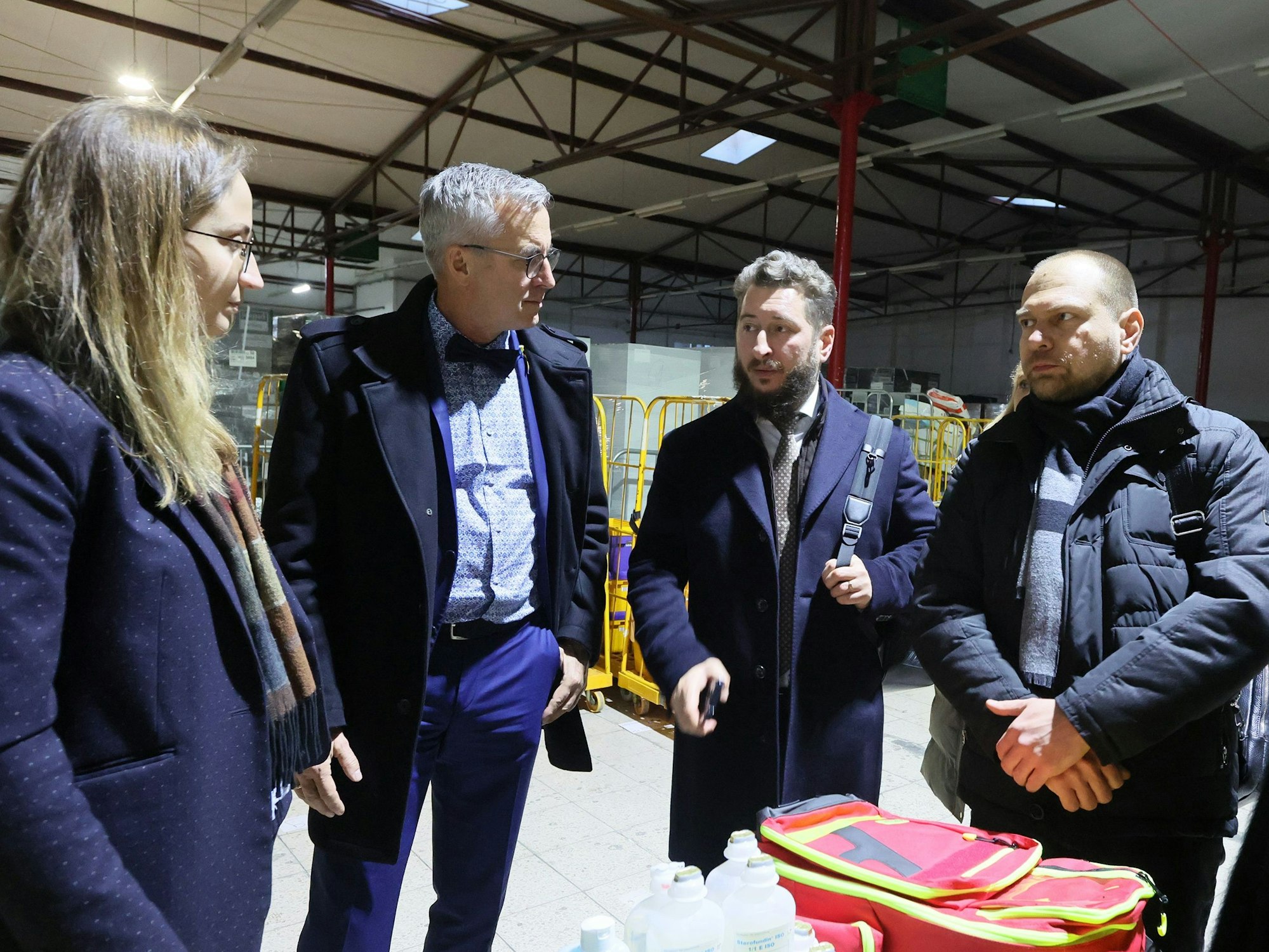 Eine Gruppe von Menschen steht in einem Lager für Hilfsgüter.