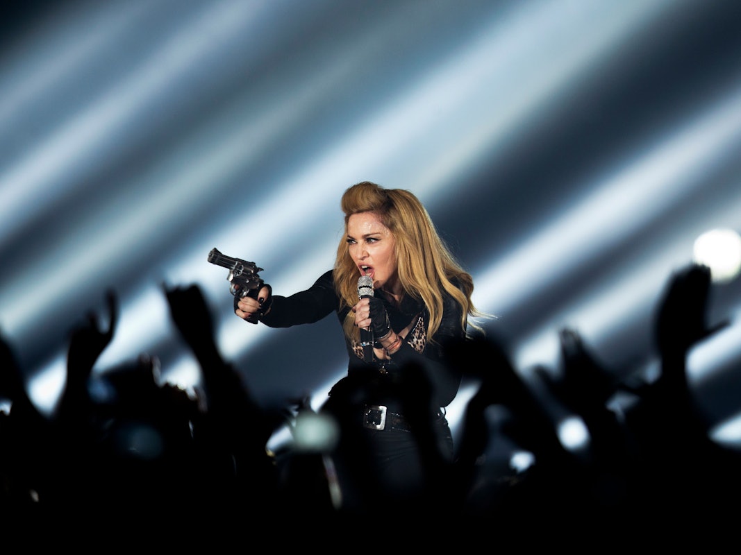 Die US-amerikanische Sängerin Madonna steht in der Lanxess-Arena in Köln mit einer Waffe auf der Bühne.