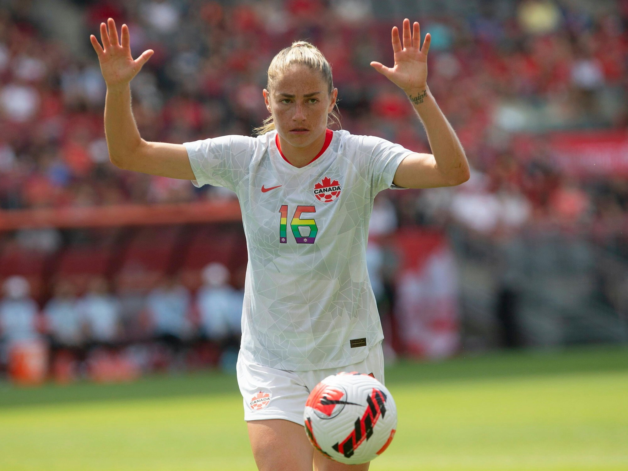 Fußballerin Janine Beckie (Kanada) hebt auf dem Spielfeld die Hände hoch.