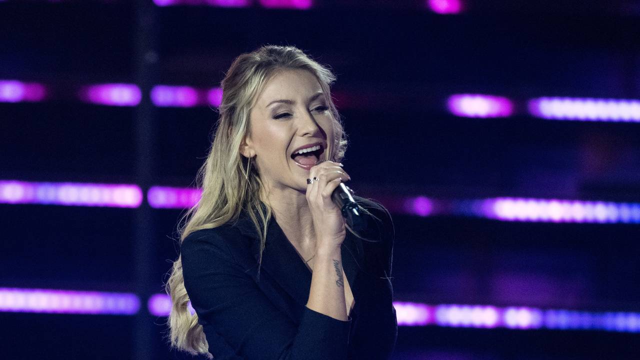 Die deutsche Sängerin Anna-Carina Woitschack steht in der Fernsehshow „Das große Schlagerjubiläum 2022“ in Leipzig auf der Bühne und singt ins Mikrfon. Die Blondine trägt ein schwarzes, bauchfreies Oberteil.