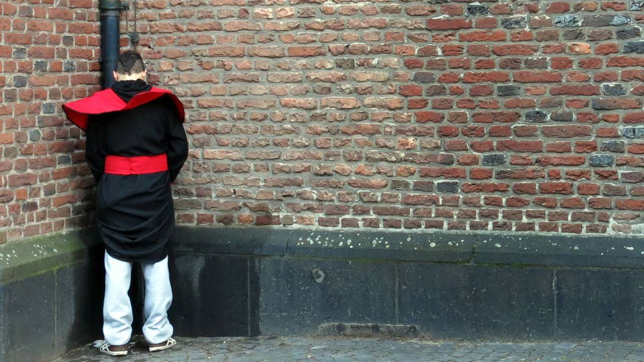 Ein Wildpinkler steht in der Altstadt von Düsseldorf an einer Kirchenwand.