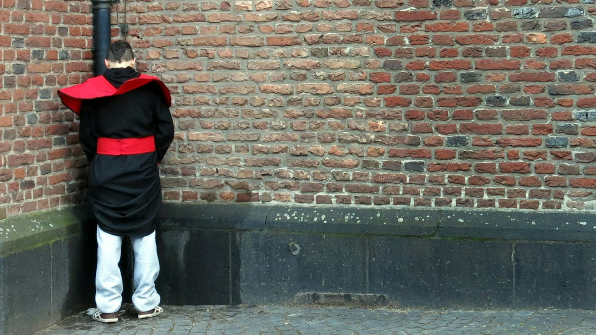 Ein Wildpinkler steht in der Altstadt von Düsseldorf an einer Kirchenwand.