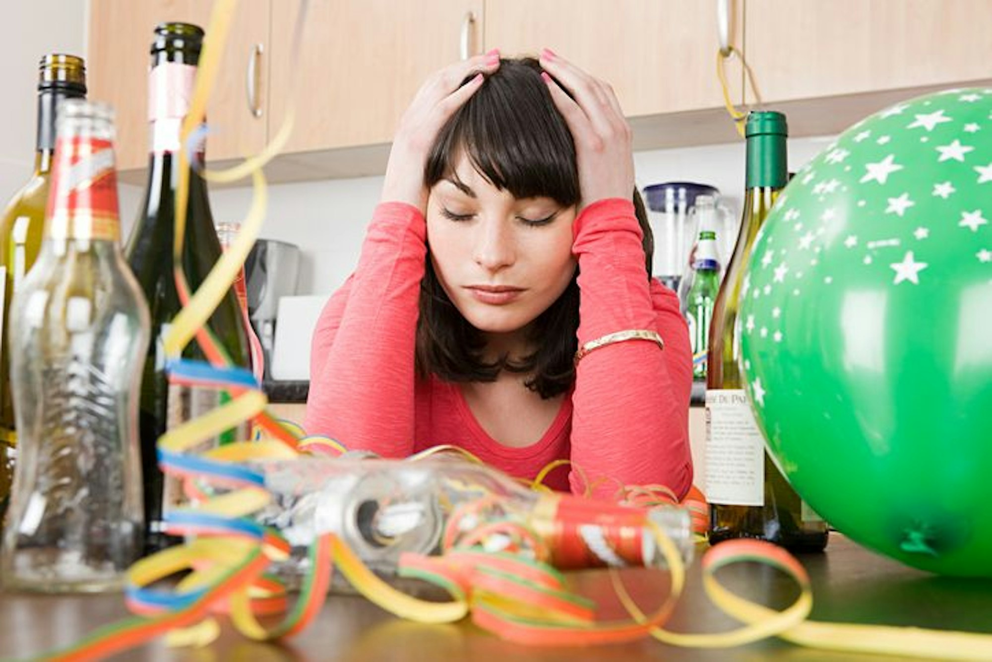 Frau mit Kater nach einer Party stützt den Kopf auf ihre Hände