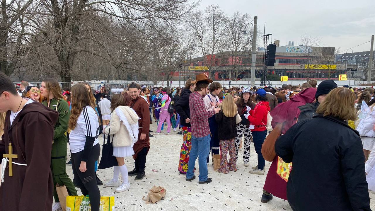 Menschen feiern Karneval auf den abgedeckten Uniwiesen.