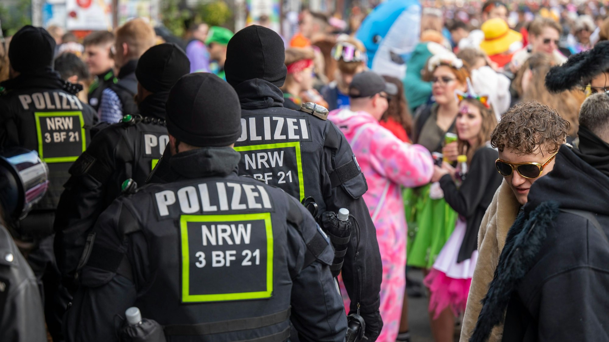 Einsatzkräfte der Polizei bahnen sich den Weg durch feiernde Jecken.