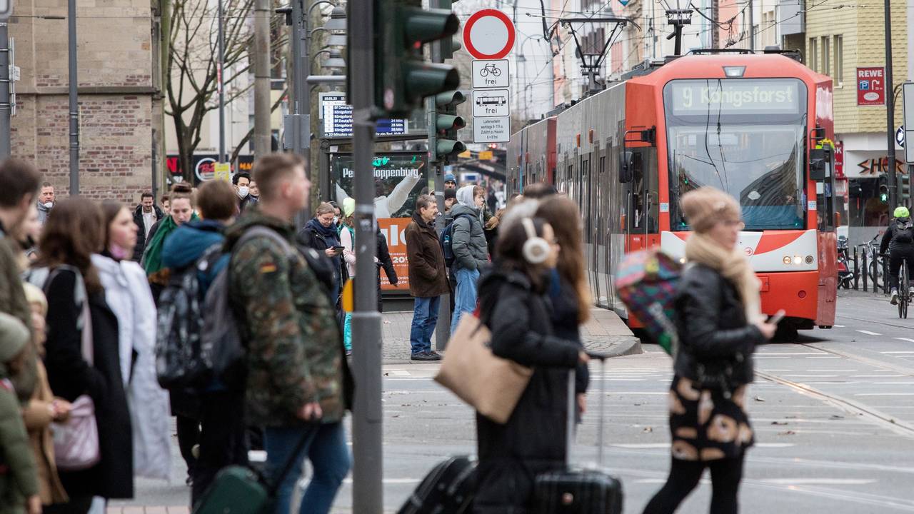 Menschen warten am Zülpicher Platz auf die KVB, im Hintergrund fährt eine Linie 9 heran.