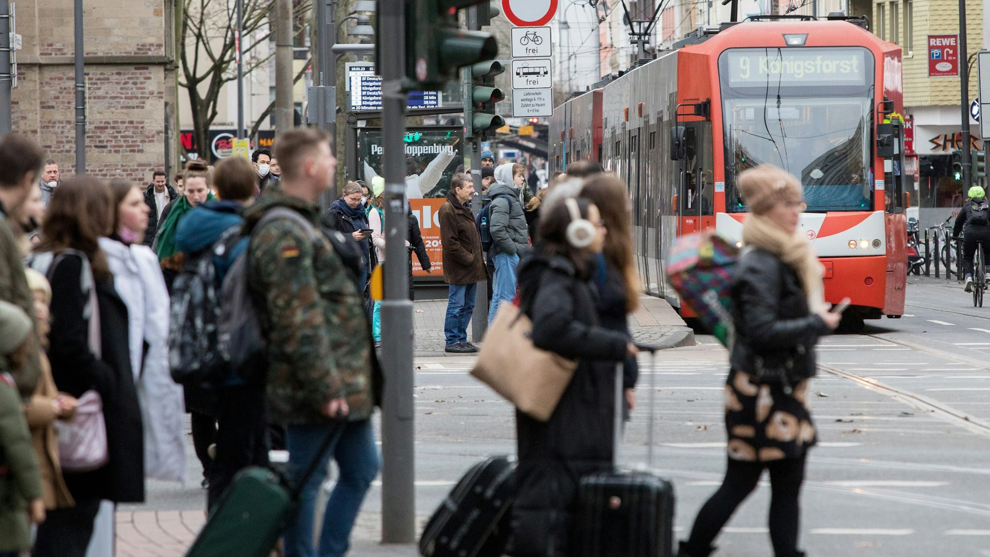 Menschen warten am Zülpicher Platz auf die KVB, im Hintergrund fährt eine Linie 9 heran.