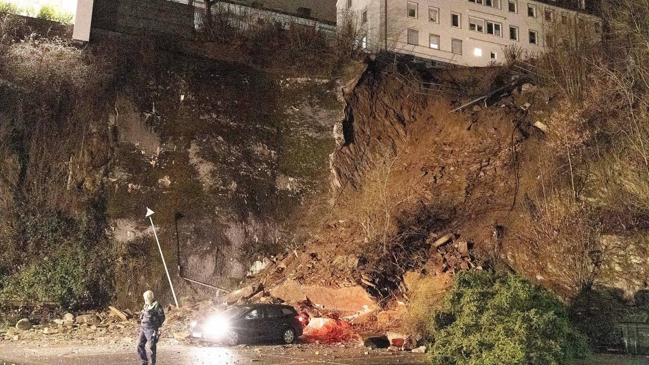 Ein Auto steht noch unterhalb eines abgerutschten Hanges. Wegen des Hangrutsches haben Einsatzkräfte der Polizei und Feuerwehr mehrere Wohnungen am Samstagmorgen (18. Februar 2023) evakuiert.