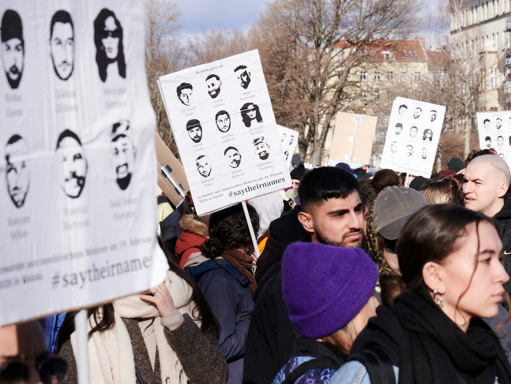 Die Namen und Gesichter der neun Menschen, die vor drei Jahren in Hanau ermordet wurden, sind auf Plakaten zu sehen, die Menschen bei der Gedenkveranstaltung eines Bündnisses von Initiativen und Organisationen auf dem Oranienplatz halten. Ein 43-jähriger Deutscher hatte am 19. Februar 2020 in Hanau neun Menschen aus rassistischen Motiven ermordet.