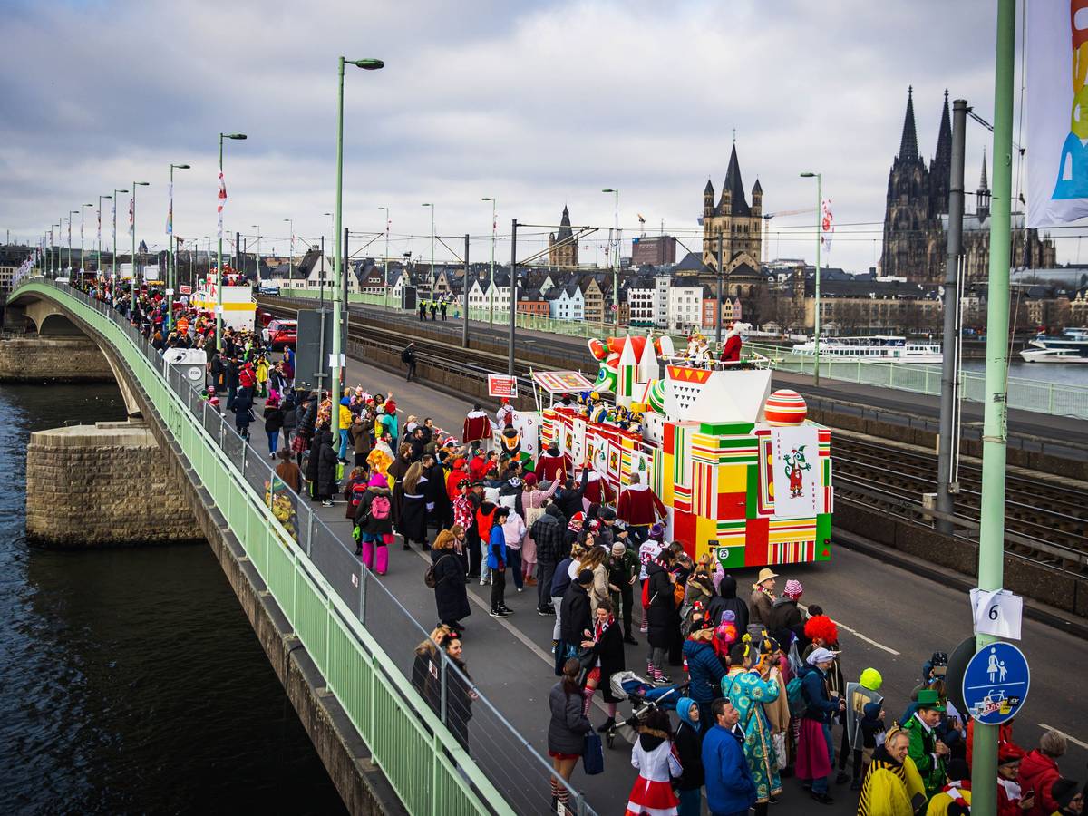 Eine Gruppe im Kölner Rosenmontagszug passiert die Deutzer Brücke, im Hintergrund der Kölner Dom.