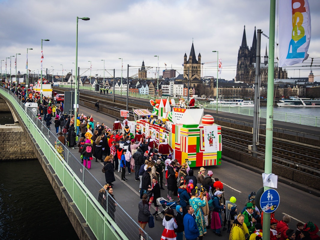 Eine Gruppe im Kölner Rosenmontagszug passiert die Deutzer Brücke, im Hintergrund der Kölner Dom.