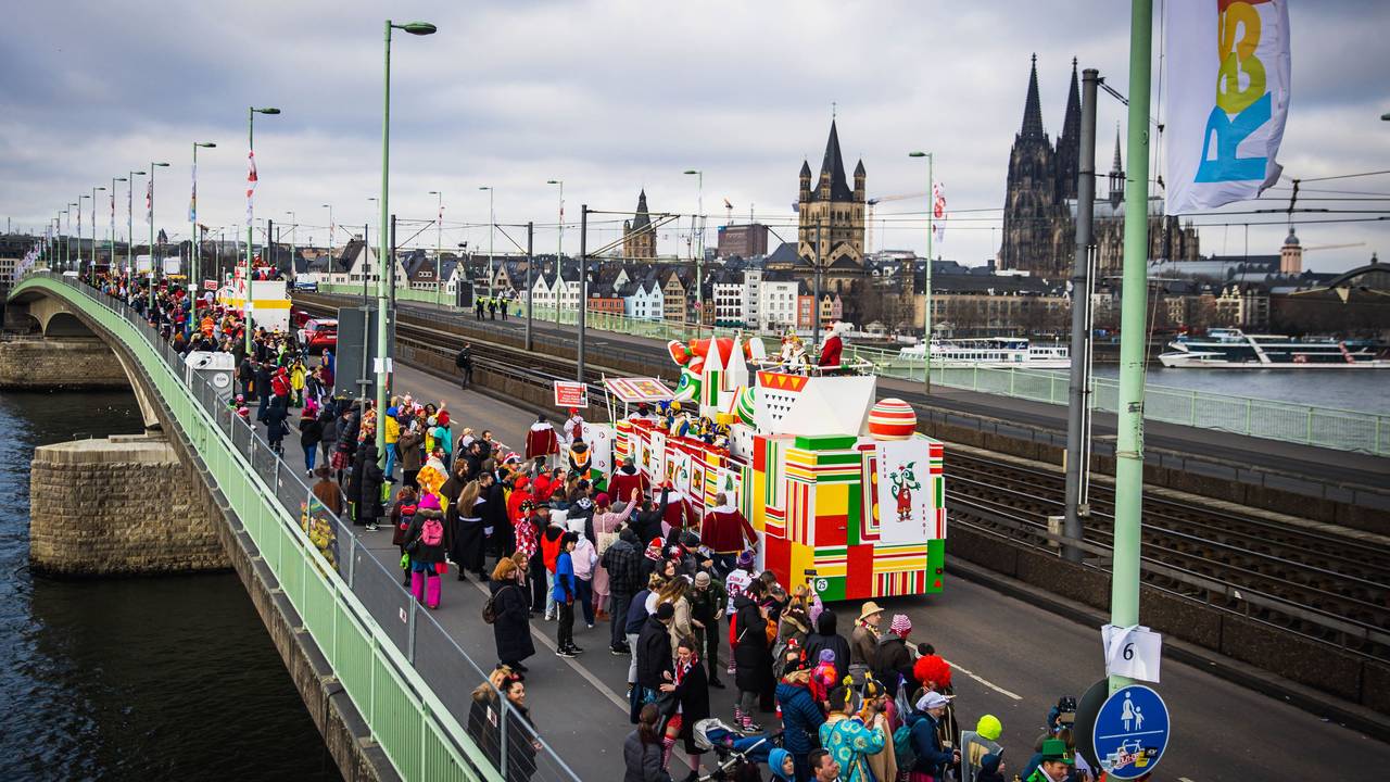Eine Gruppe im Kölner Rosenmontagszug passiert die Deutzer Brücke, im Hintergrund der Kölner Dom.