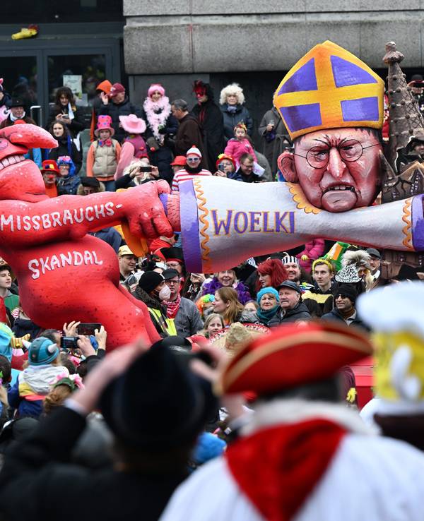 Ein Mottowagen zeigt den Teufel, der am Kölner Kardinal Woelki zerrt, der sich am Kölner Dom festklammert.