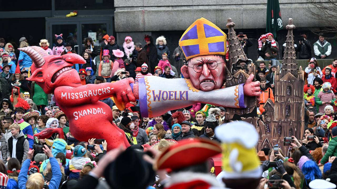 Ein Mottowagen zeigt den Teufel, der am Kölner Kardinal Woelki zerrt, der sich am Kölner Dom festklammert.