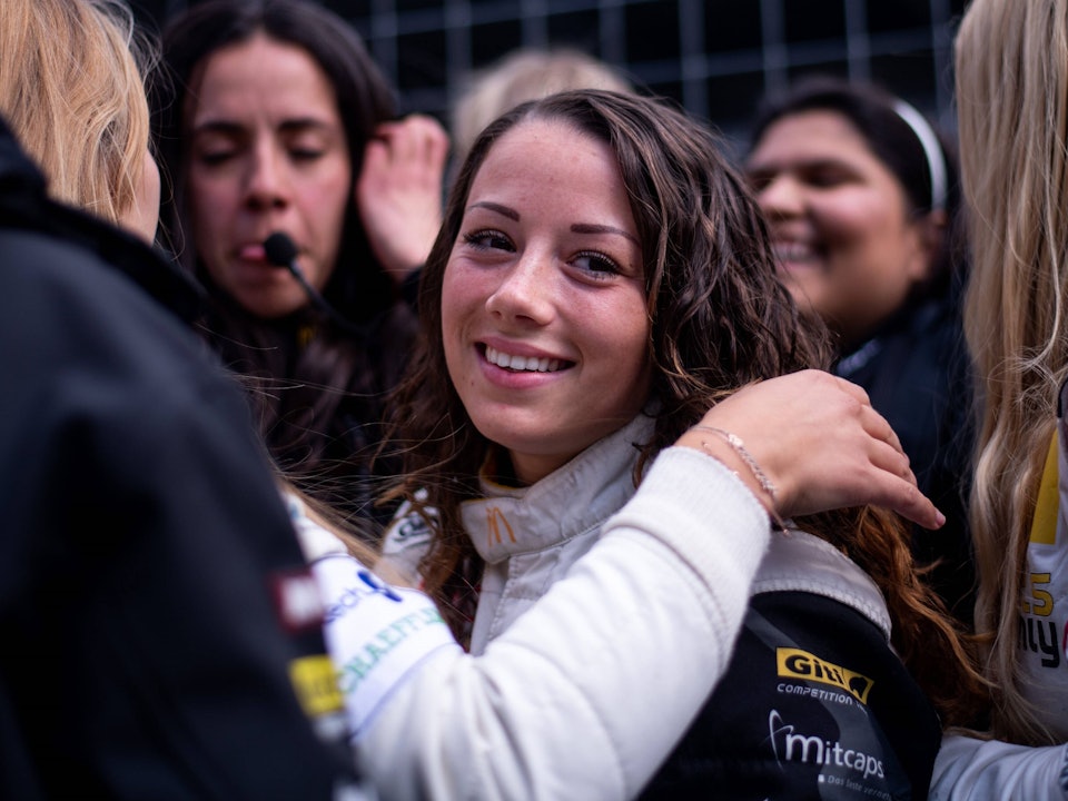 Carrie Schreiner blickt beim 24-Stunden-Rennen auf dem Nürburgring in der Box in die Kamera.