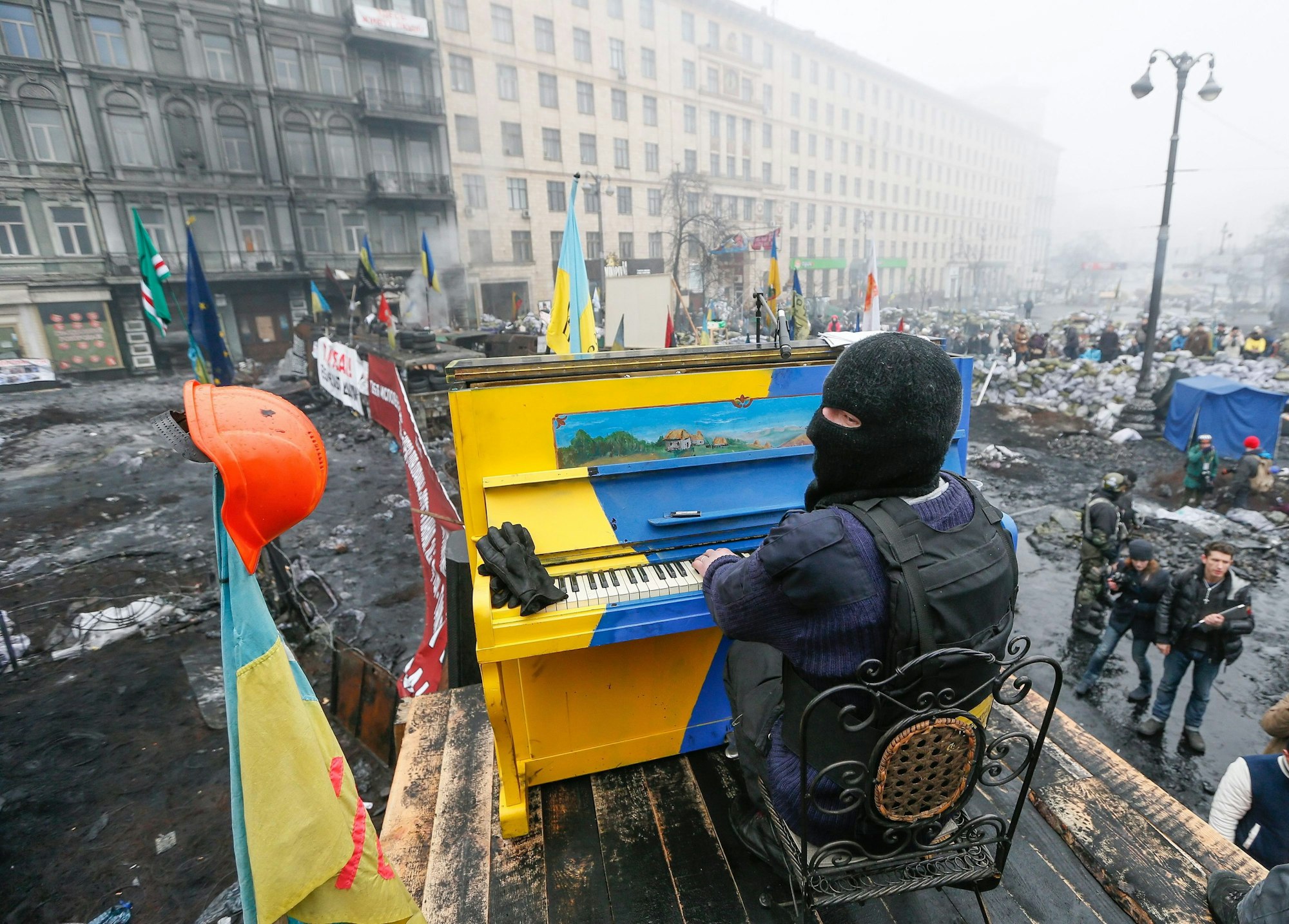 Ein am 22. November 2014 veröffentlichtes Bild aus dem Archiv zeigt einen ukrainischen Demonstranten, der während der anhaltenden Euromaidan-Proteste in Kyjiw auf einer Barrikade Klavier spielt. Das Klavier ist in den Nationalfarben der Ukraine gestrichen. Es liegen Trümmer drumherum.