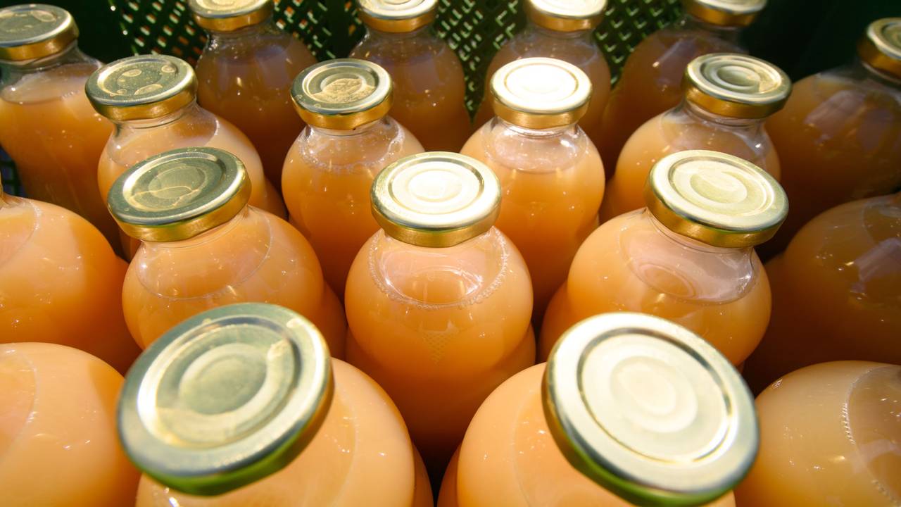 Das Symbolfoto von 2021 zeigt mehrere Glasflaschen mit Deckel. In den Flaschen befindet sich ein orangefarbener Saft.