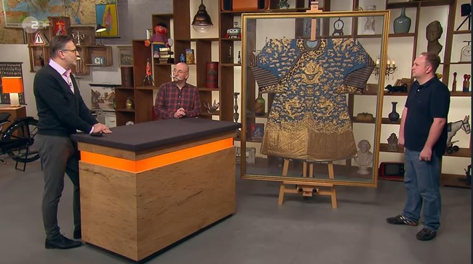 Lars Petersohn (r.) verkaufte bei „Bares für Rares“ eine chinesische Drachenrobe. Experte Detlev Kümmel und Moderator Horst Lichter zeigten sich begeistert.