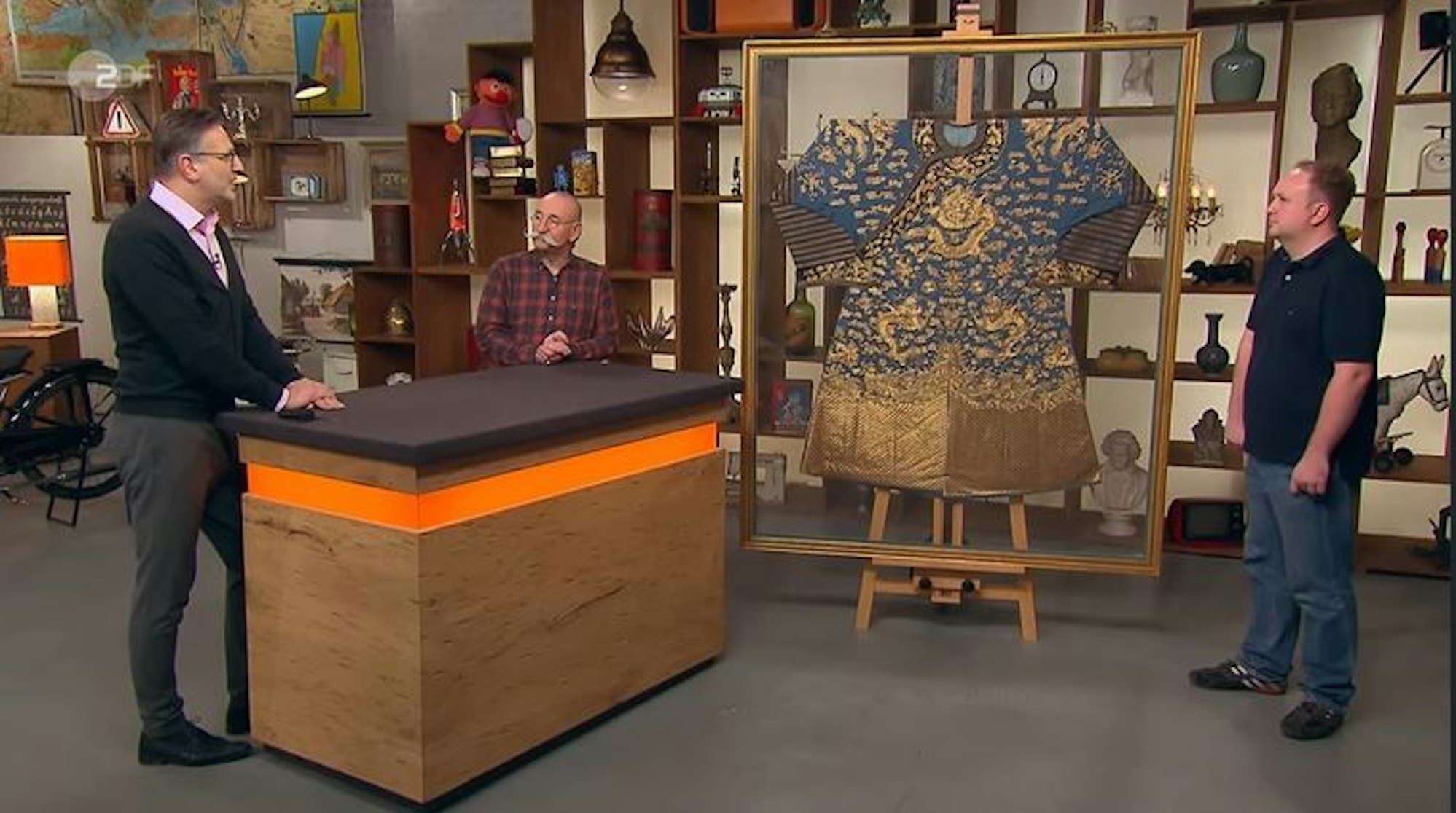 Lars Petersohn (r.) verkaufte bei „Bares für Rares“ eine chinesische Drachenrobe. Experte Detlev Kümmel und Moderator Horst Lichter zeigten sich begeistert.