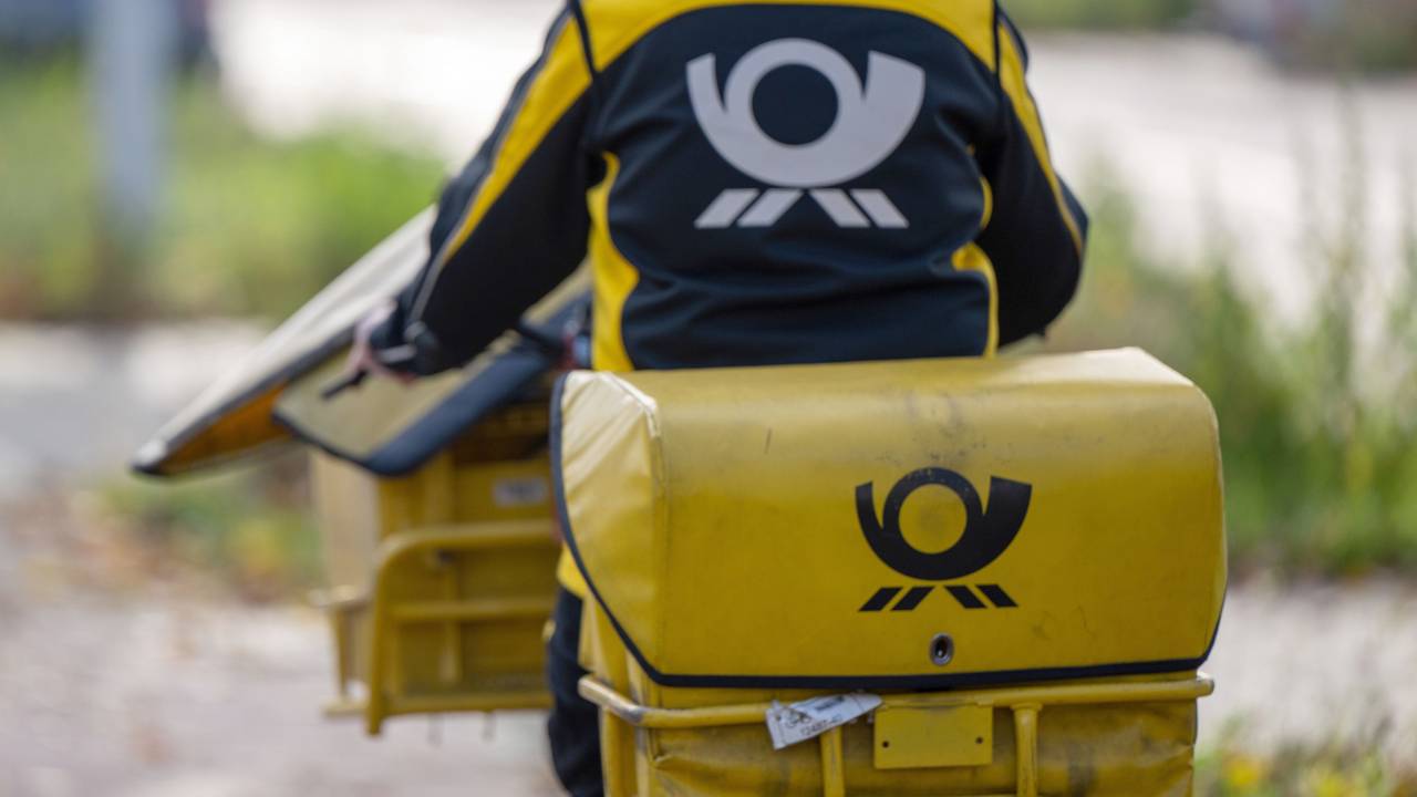 Eine Briefträgerin der Deutschen Post fährt auf ihrem Postfahrrad.