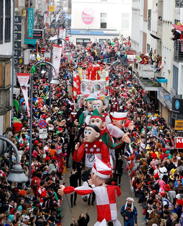 Teile des Kölner Rosenmontagszugs gehen zwischen feiernden Jecken auf der Severinstraße entlang.