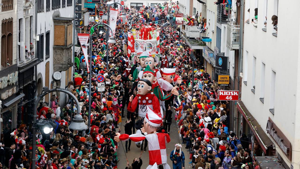 Teile des Kölner Rosenmontagszugs gehen zwischen feiernden Jecken auf der Severinstraße entlang.