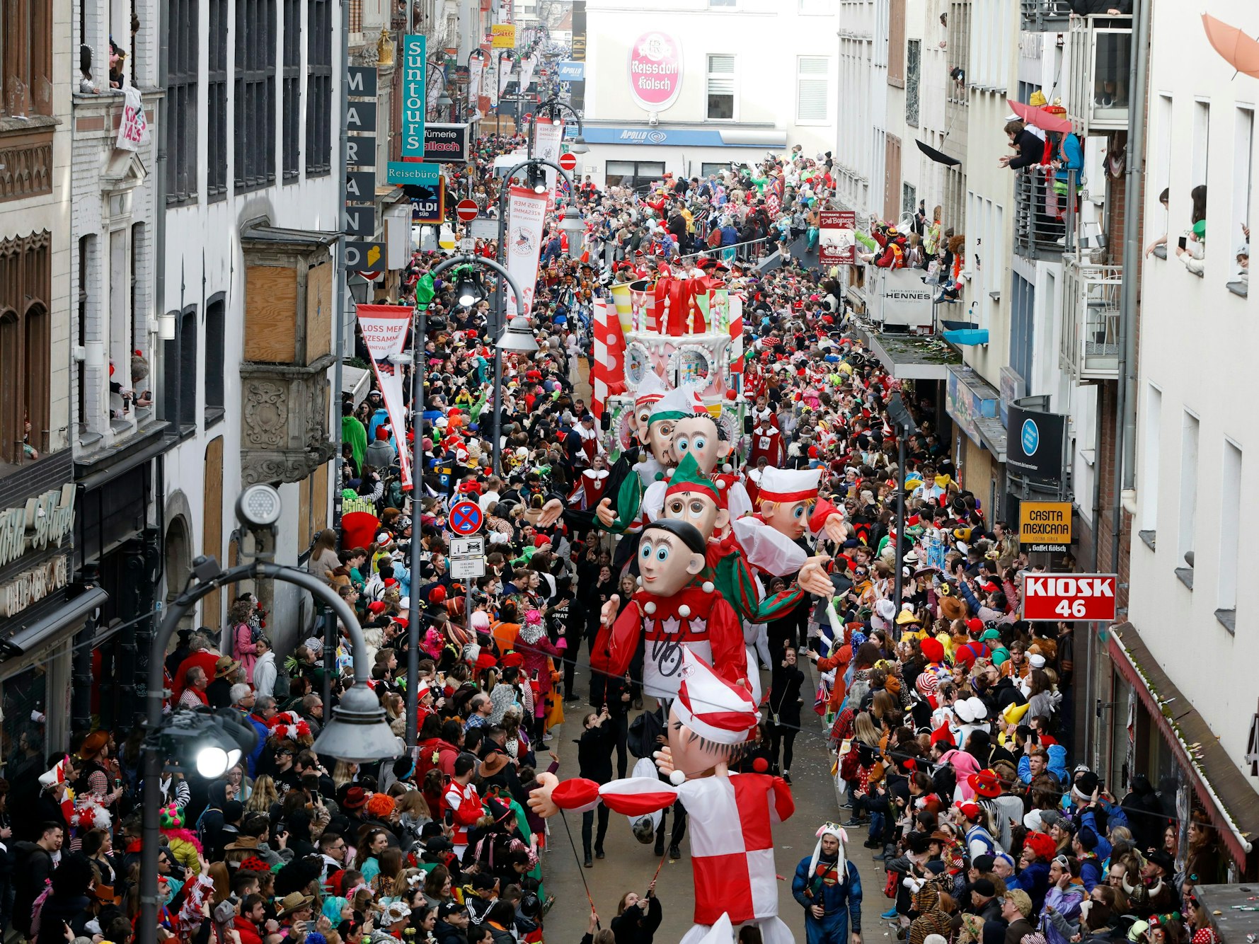 Teile des Kölner Rosenmontagszugs gehen zwischen feiernden Jecken auf der Severinstraße entlang.