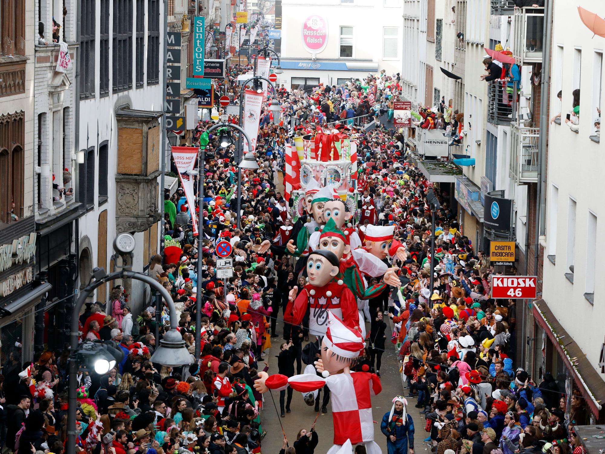 Teile des Kölner Rosenmontagszugs gehen zwischen feiernden Jecken auf der Severinstraße entlang.