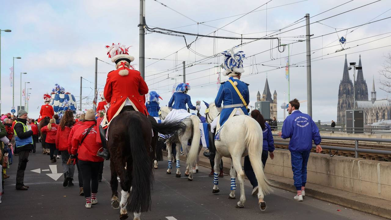 Funken reiten während des Rosenmontagszuges mit Pferden über die Deutzer Brücke.